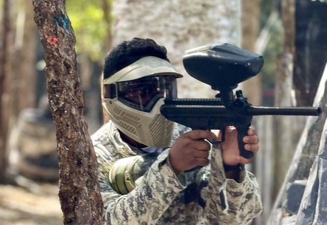 A paintball player taking aim in full gear