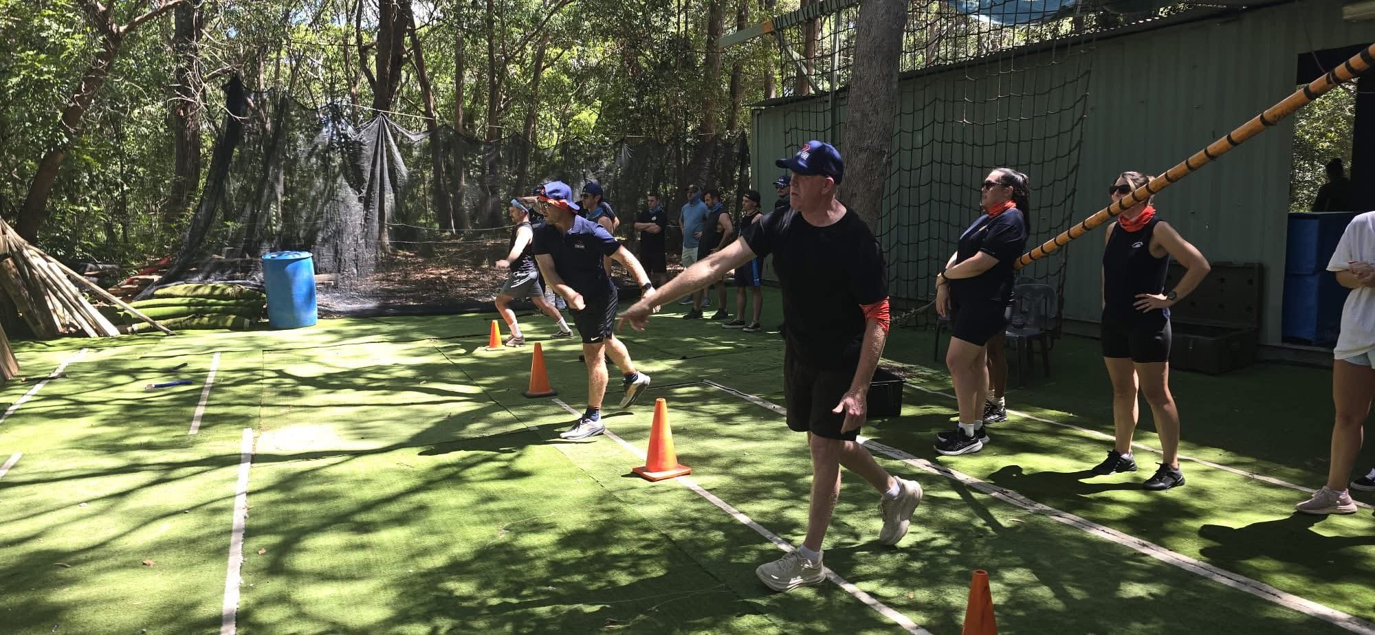 A group at the outdoor axe throwing lanes at XperiencesHQ, coach supervising