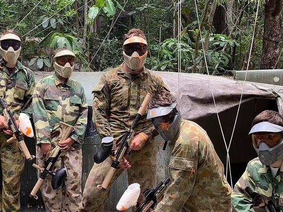 A paintball team in full protective gear on the forest range